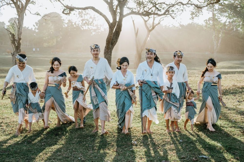Wedding group jumping shot with matching light blue outfits in golden sunlight.