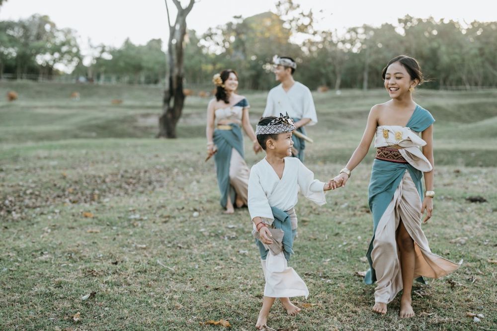 People in coordinated blue and white outfits play together in an outdoor setting at sunset.