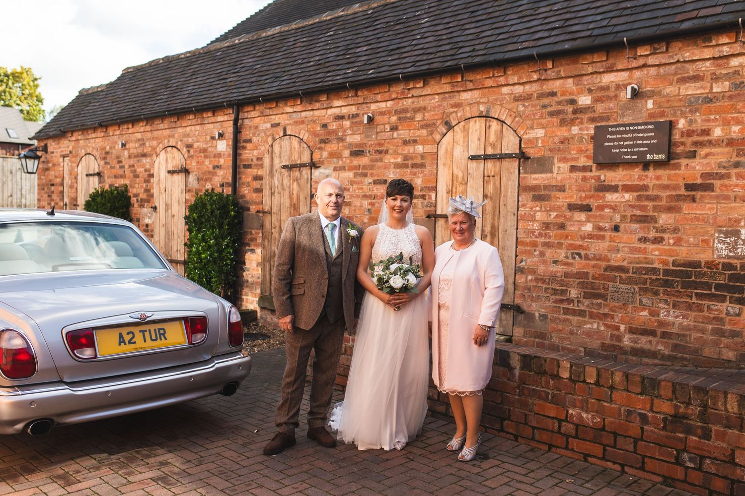 Vintage Rolls Royce classic car parked outside a rustic brick building for a wedding celebration.