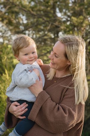 A tender moment captured between parent and baby in warm sunlight against a natural outdoor backdrop.