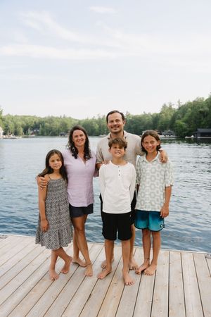 Several people stand together on a lakeside dock during a summer photo session.