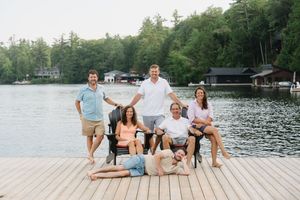 Multiple people pose for a casual photo session on a wooden dock with a lake view.