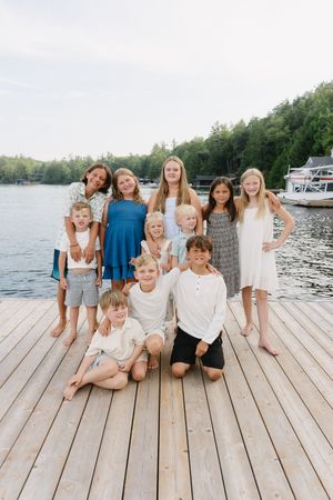 A group relaxes together on a wooden dock during a summer lakeside photo shoot.