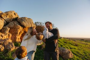 Playful family interactions captured against rocky landscape at sunset.