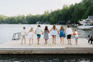 Group of people sitting on wooden dock overlooking lake and boats.