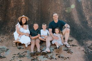 Extended family gathered on rocky terrain for outdoor photo session.