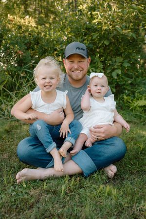Family sitting together on grassy hillside during outdoor portrait session.