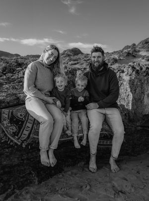 Family sitting together on rocky outcrop in black and white photography.