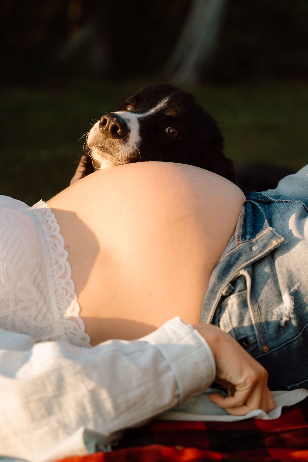 Close-up maternity photo showing pregnant belly in white lace and denim.