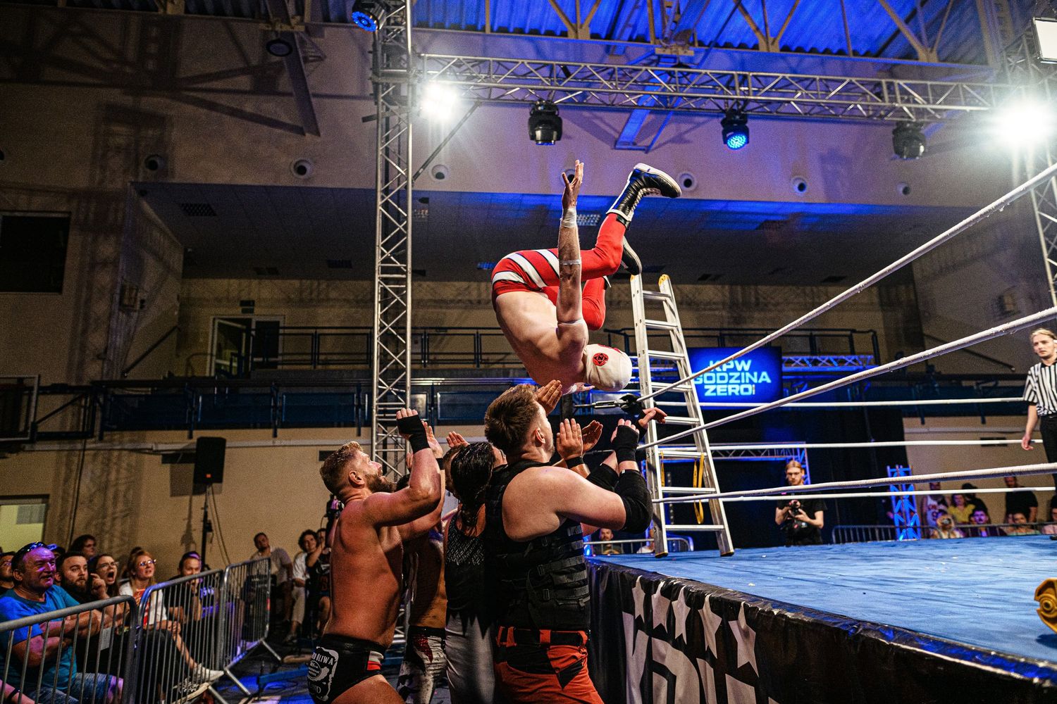 Professional wrestling match with multiple competitors performing high-flying moves in a wrestling ring.