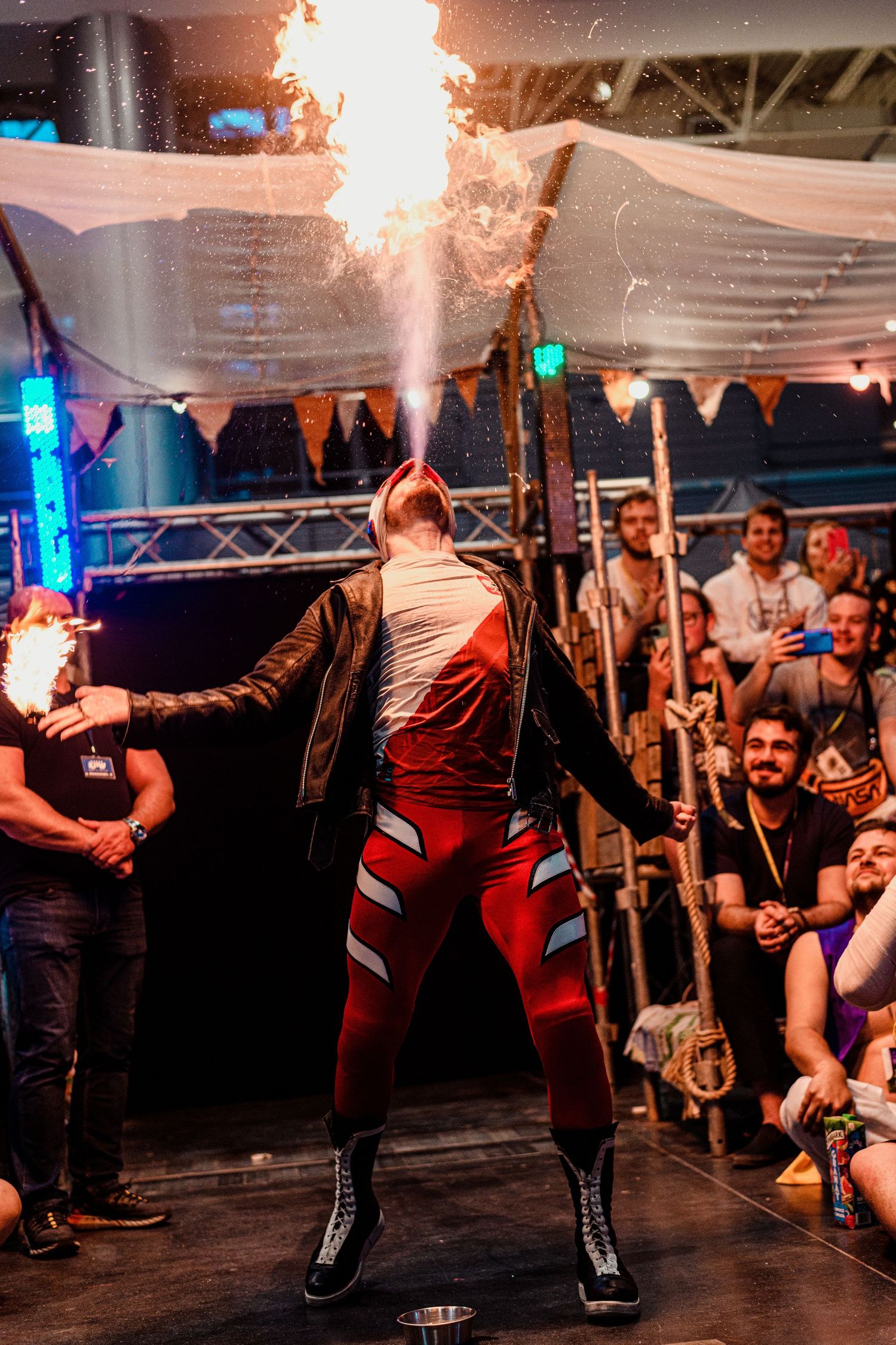 Wrestling event crowd cheers as performers engage in dramatic action in the ring.