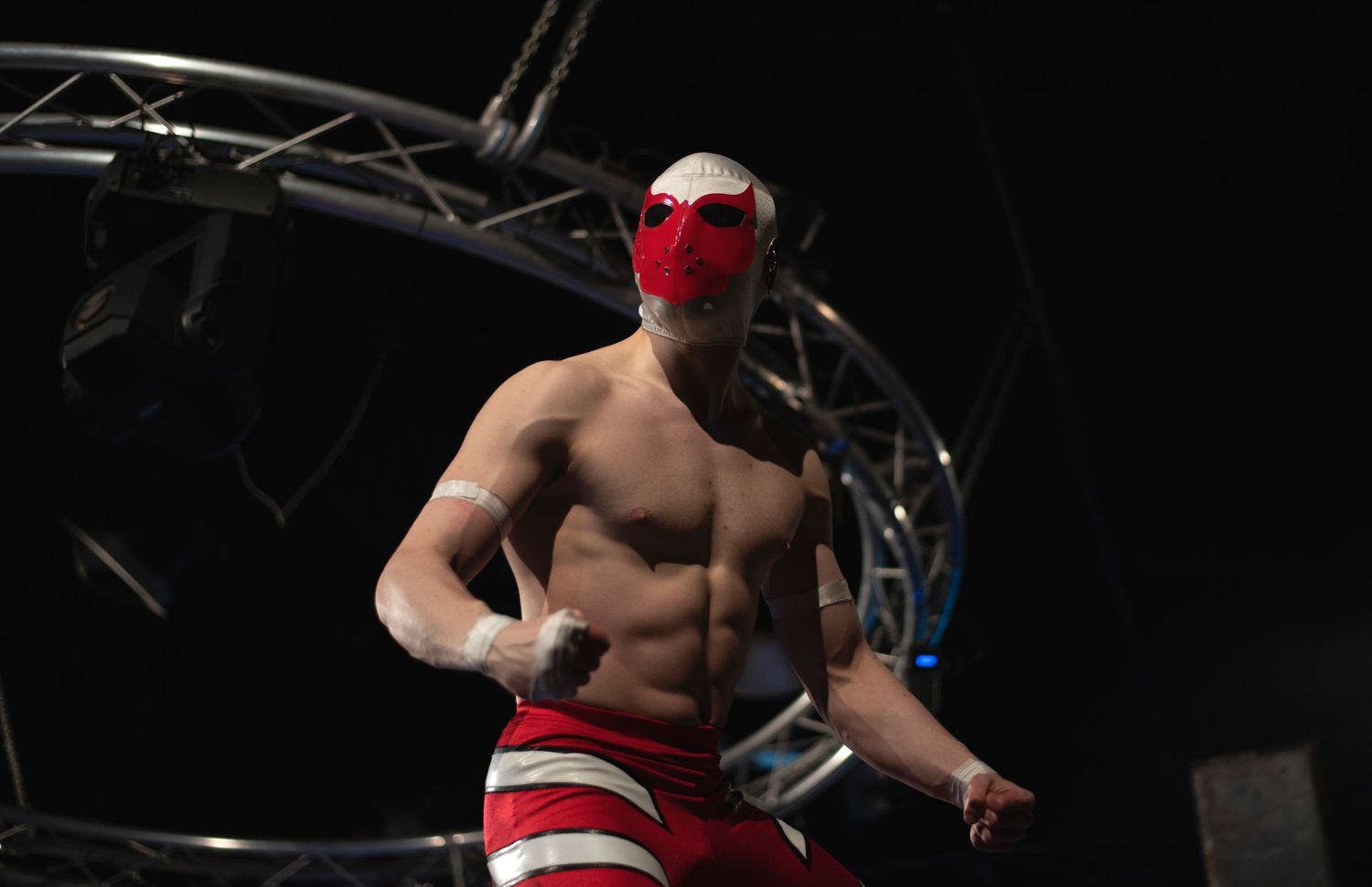 Professional wrestler performs an acrobatic flying maneuver off the top rope in a wrestling ring.