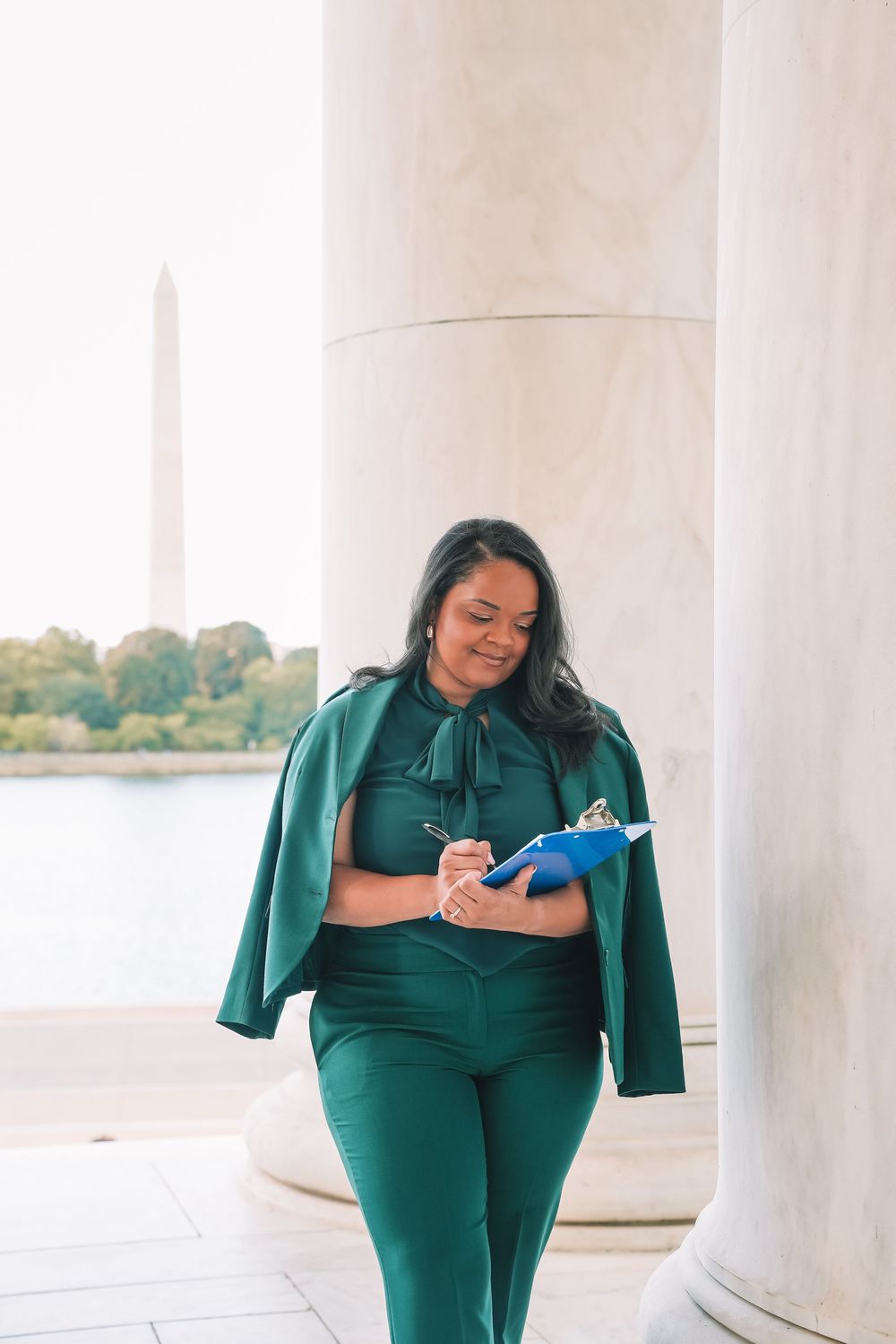 Professional portrait in emerald suit between white columns | Washington DC headshots