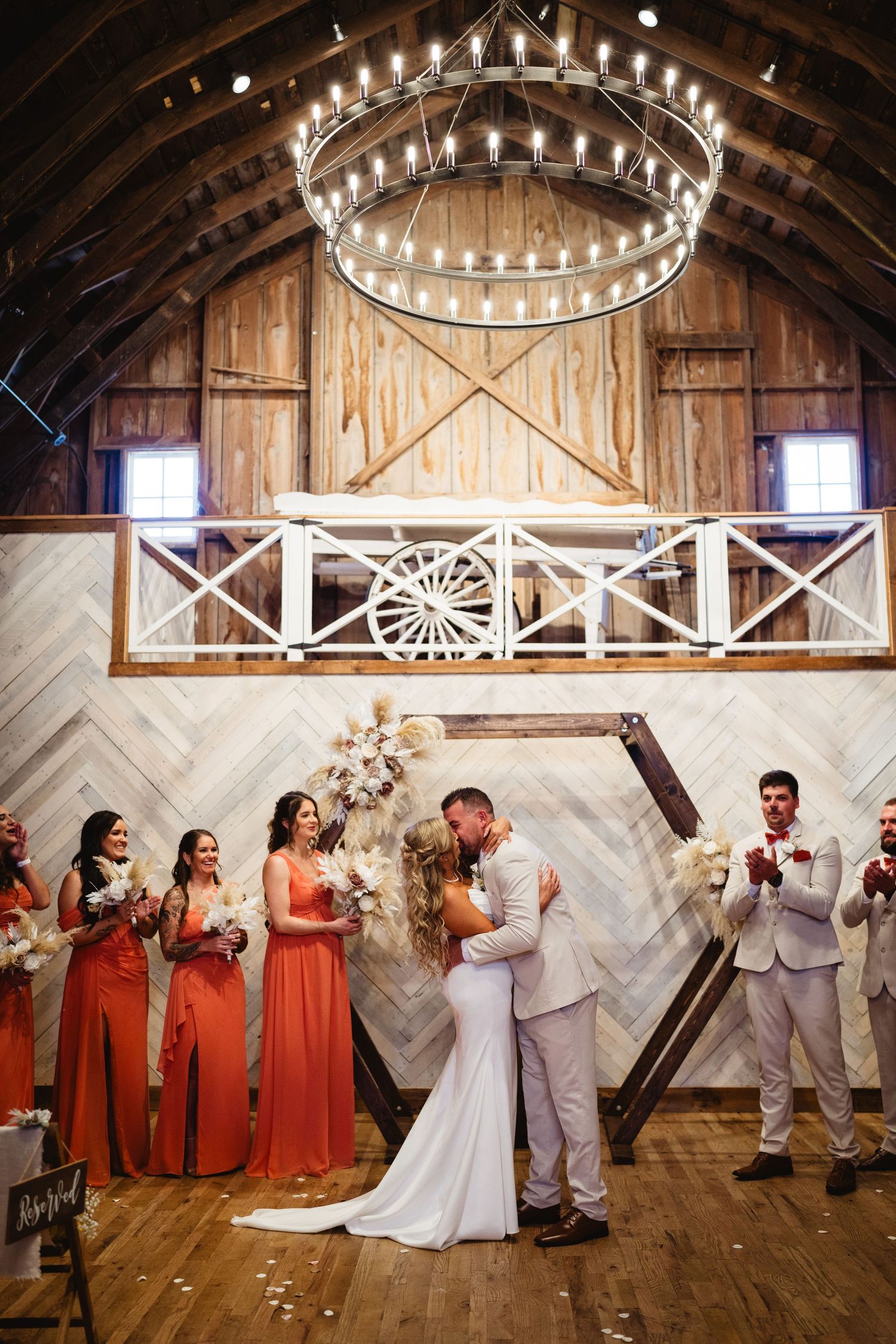 Rustic barn wedding venue showcases string lights on wooden beams with silhouettes of a bridal party dancing on hardwood floors.