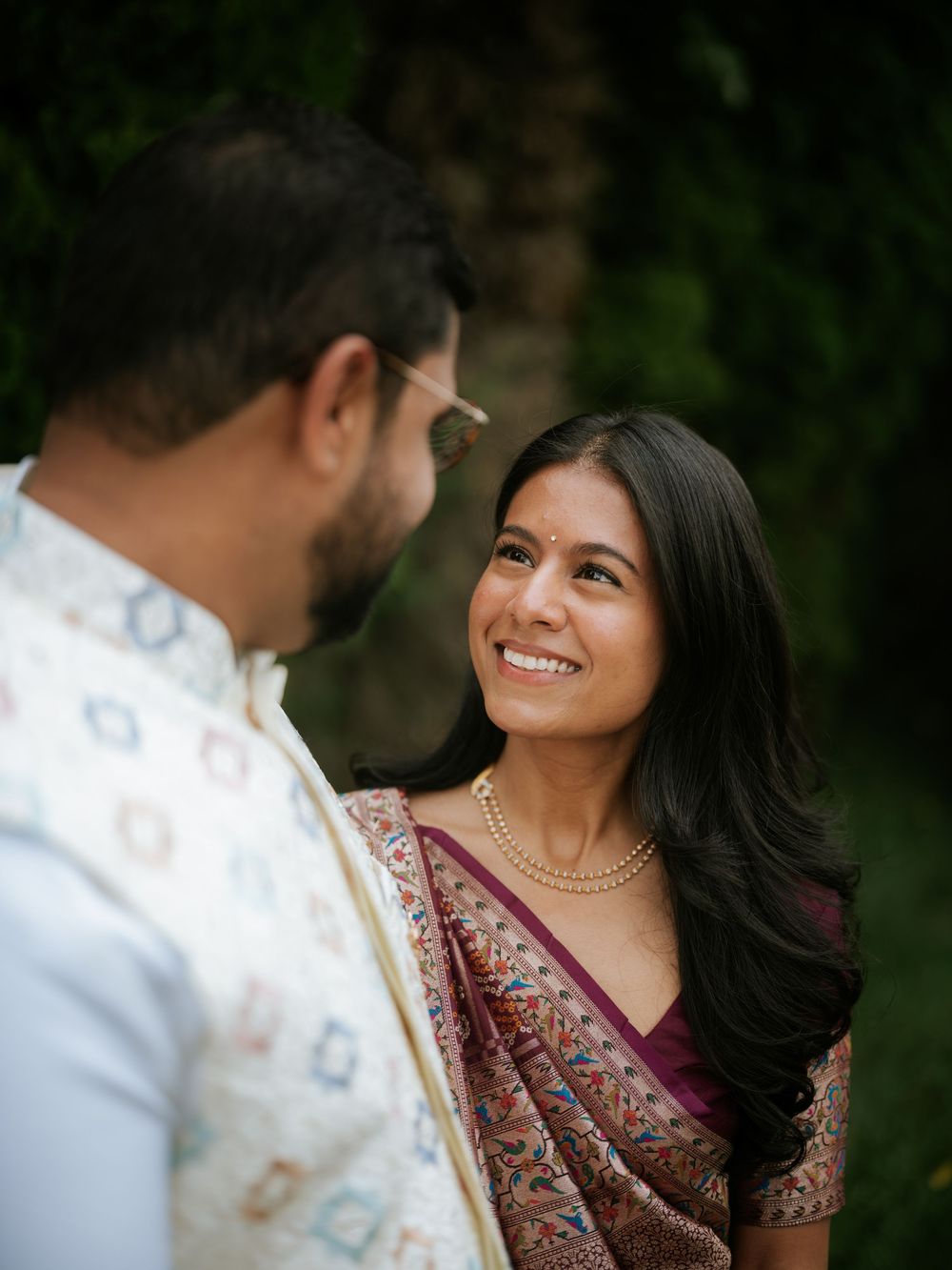 Two people in traditional wedding attire share tender moments in a lush outdoor setting with soft natural lighting.  Hilton Pearl River NY