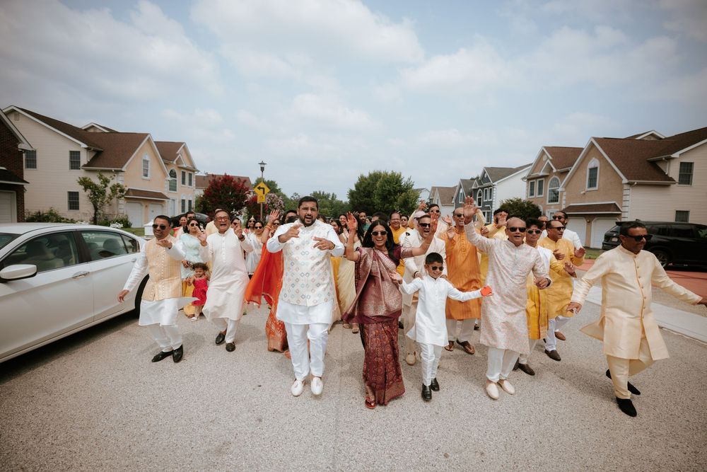 A group dressed in white and brown attire walking in formation along a residential street outside houses.  Hilton Pearl River NY