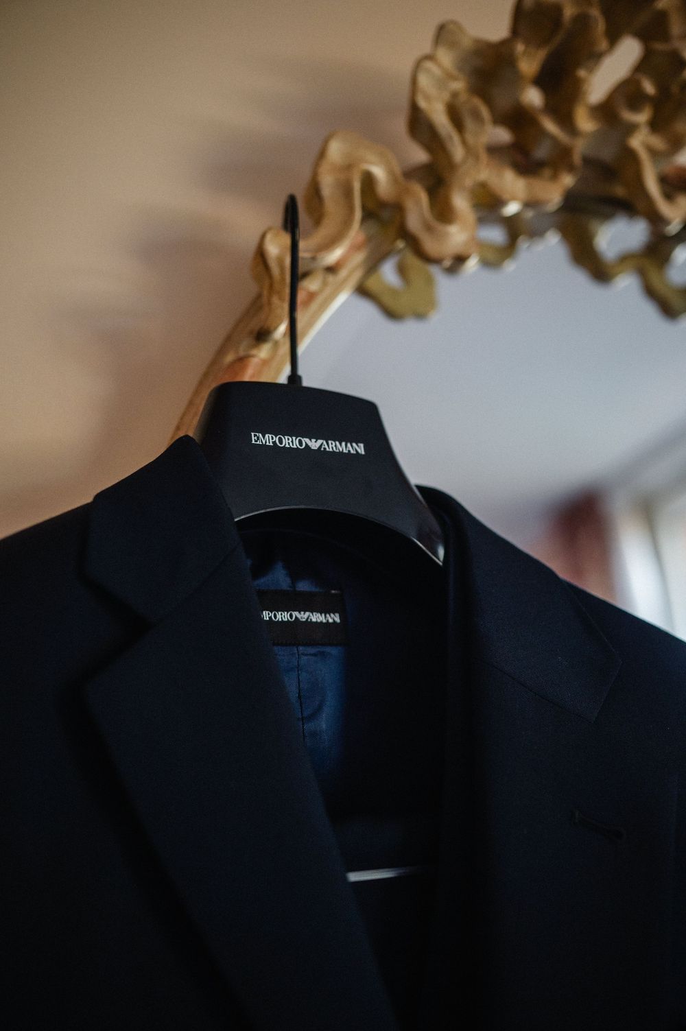 A rack of black formal suit jackets displayed on wooden hangers in a clothing store.
