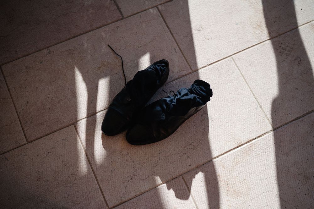 A shadow cast on tile flooring shows the outline of a person and an EV charging cable.