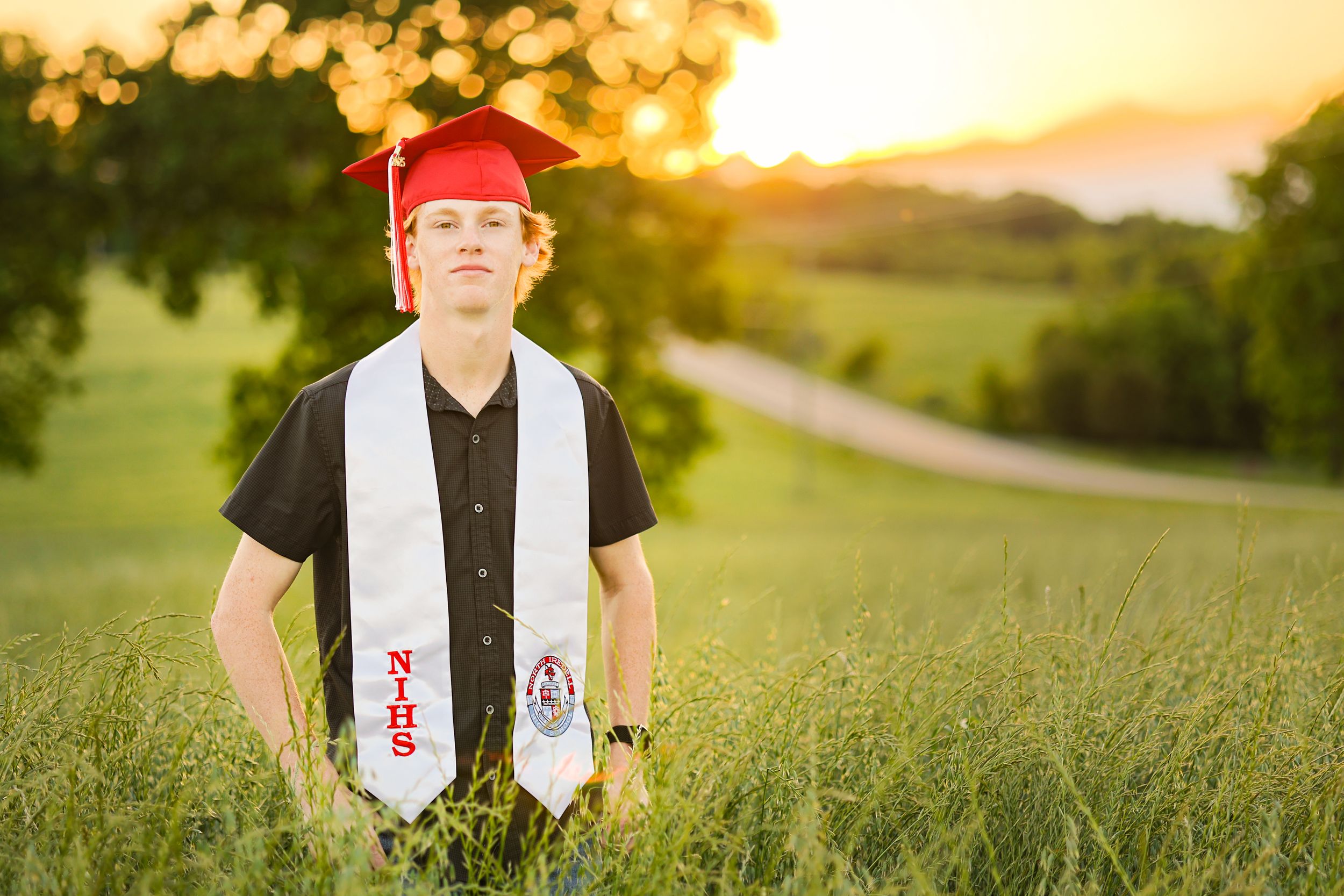 A series of graduation photos taken at sunset in a green field with golden light creating a warm atmosphere.