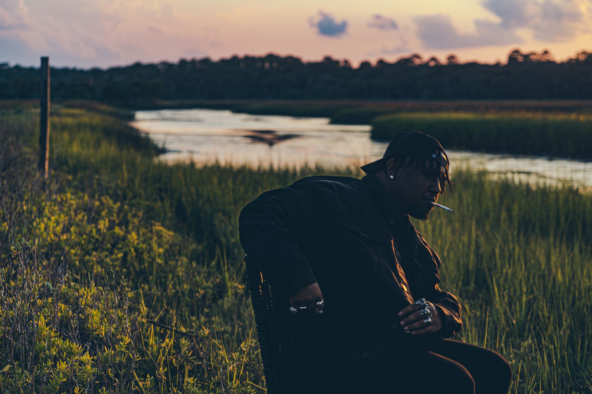 A scenic sunset view over coastal marshlands with tall grass and winding waterways in golden evening light.