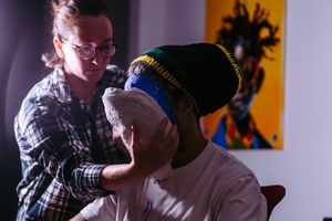 A close-up moment between two people with a colorful artwork on the yellow wall in the background.