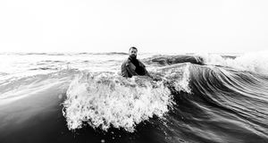 A dramatic black and white photograph of ocean waves crashing and curling at sunset.