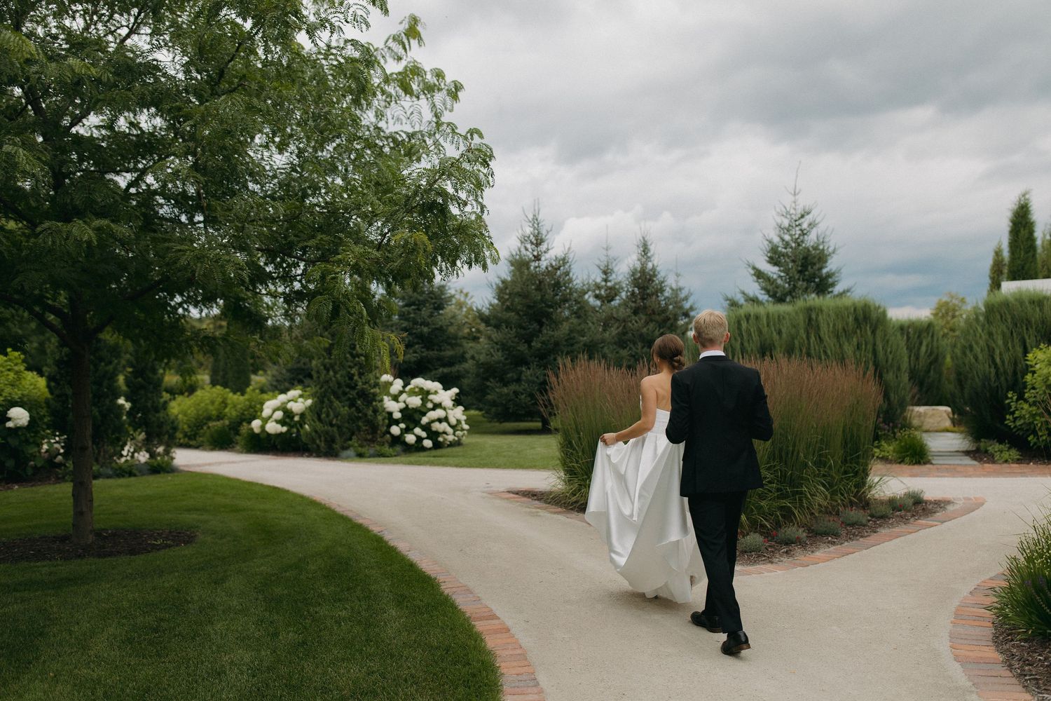Wedding ceremony venue with curved pathway through lush green gardens.