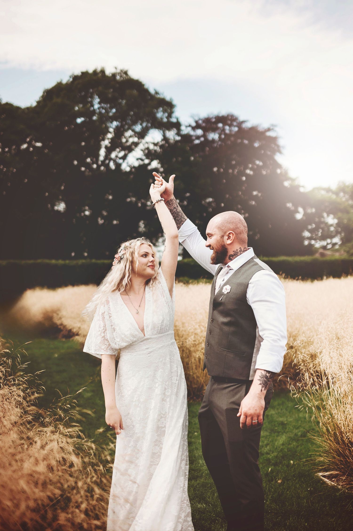 Dramatic panorama of couple in field at golden hour with mountain backdrop.