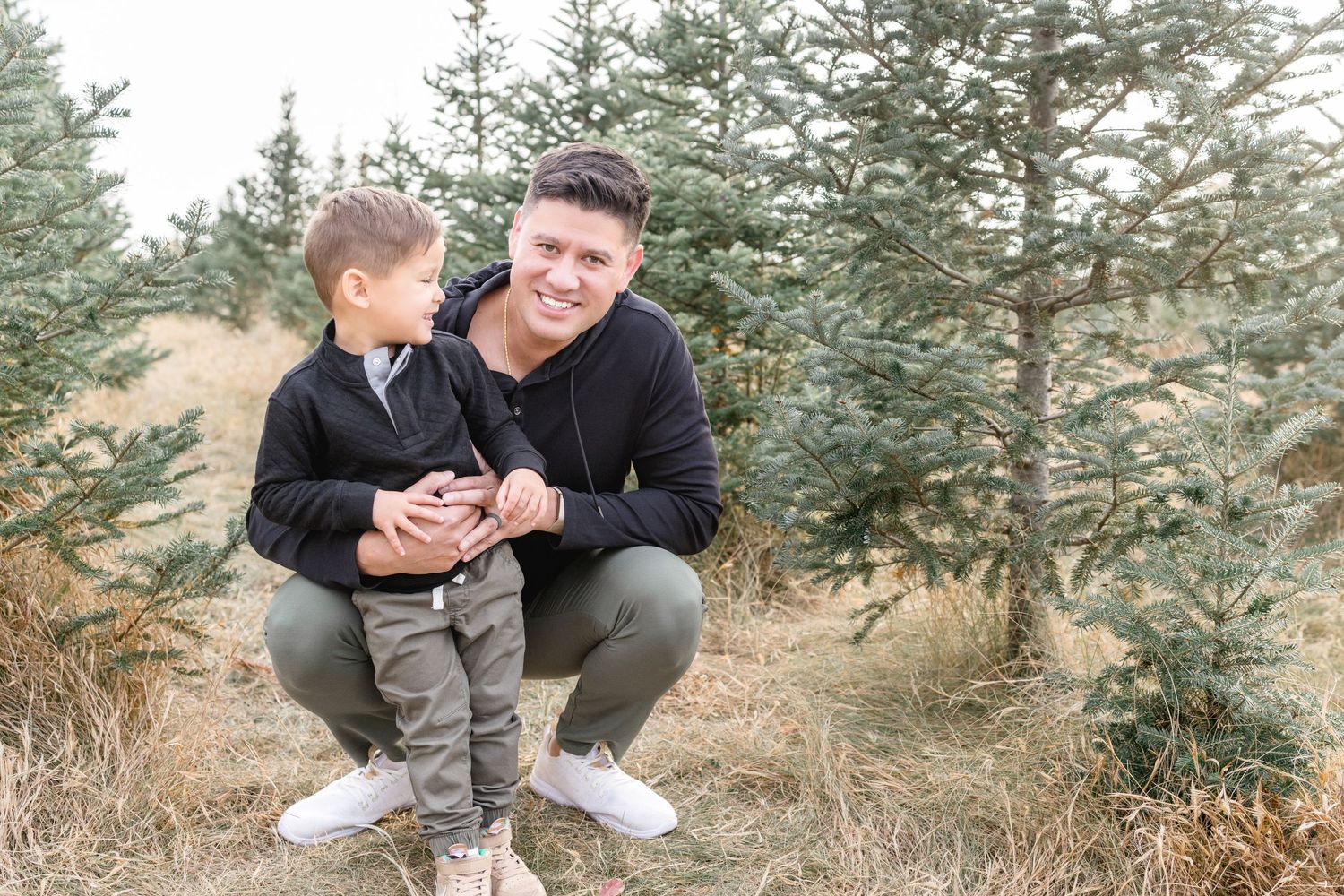 Tender moment shared between two people among pine trees.
