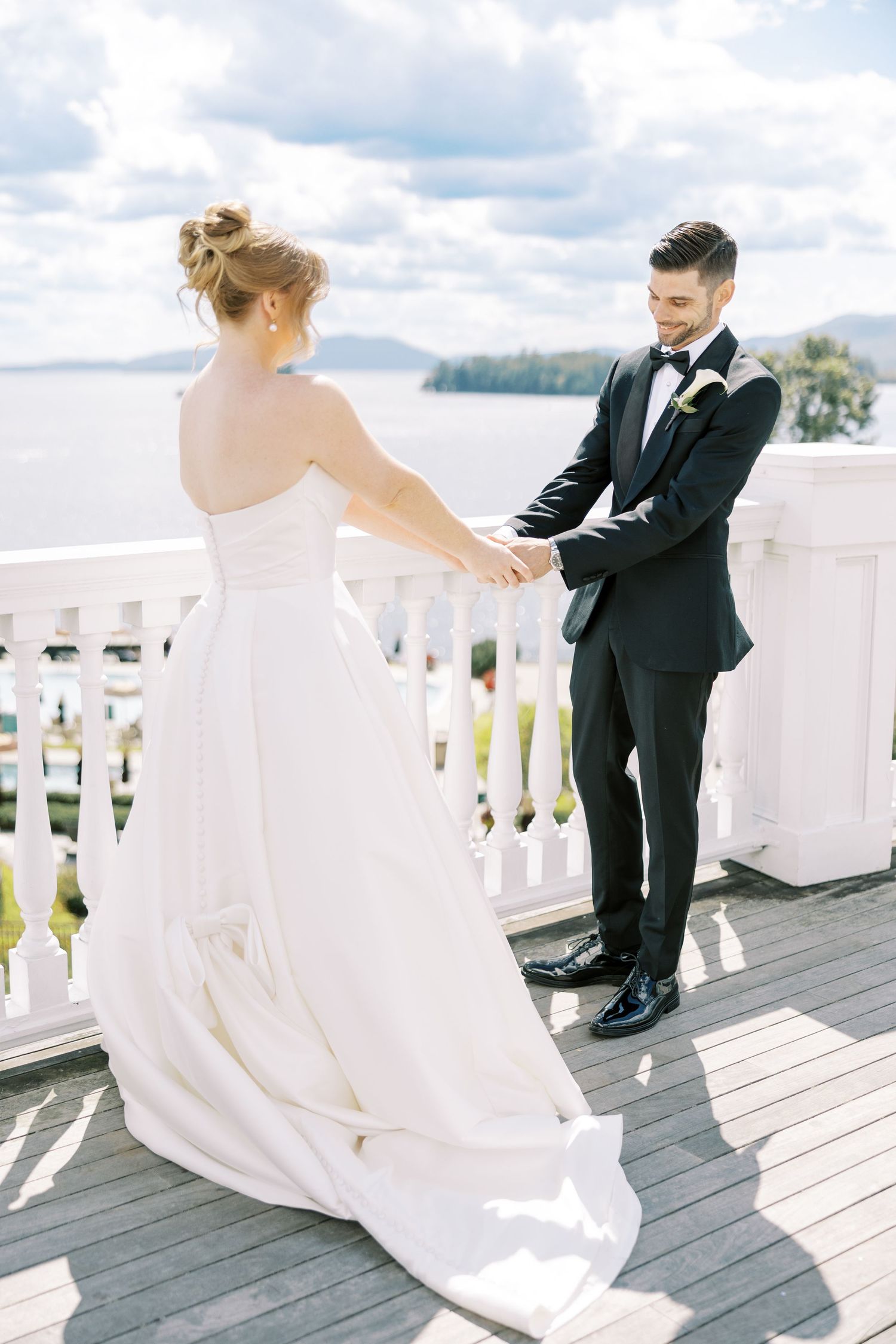 A bride and groom share a sweet moment during their first look on a white balcony deck overlooking scenic views.