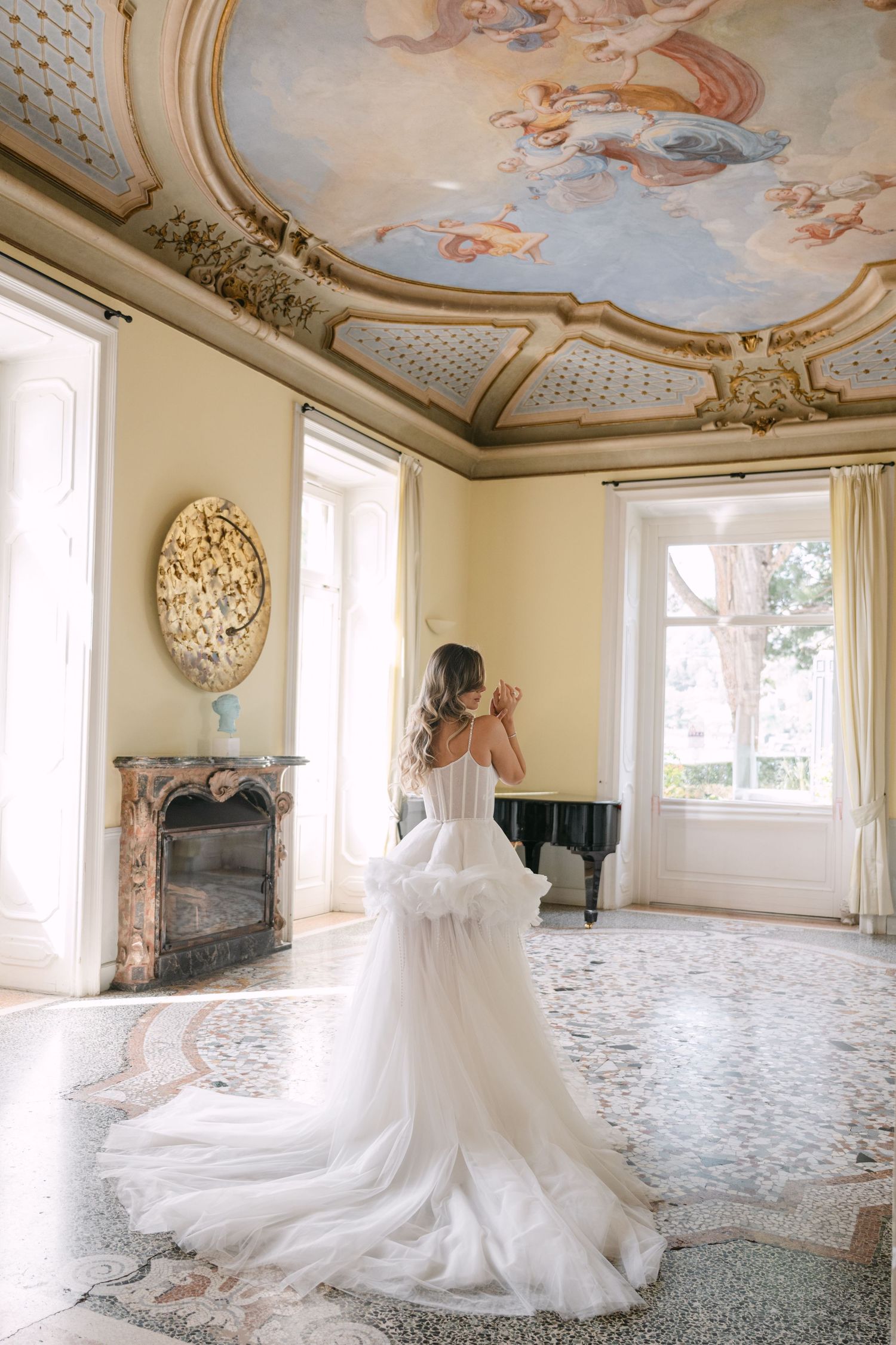 A couple dancing together under elegant stone archways with palm trees visible in the background.