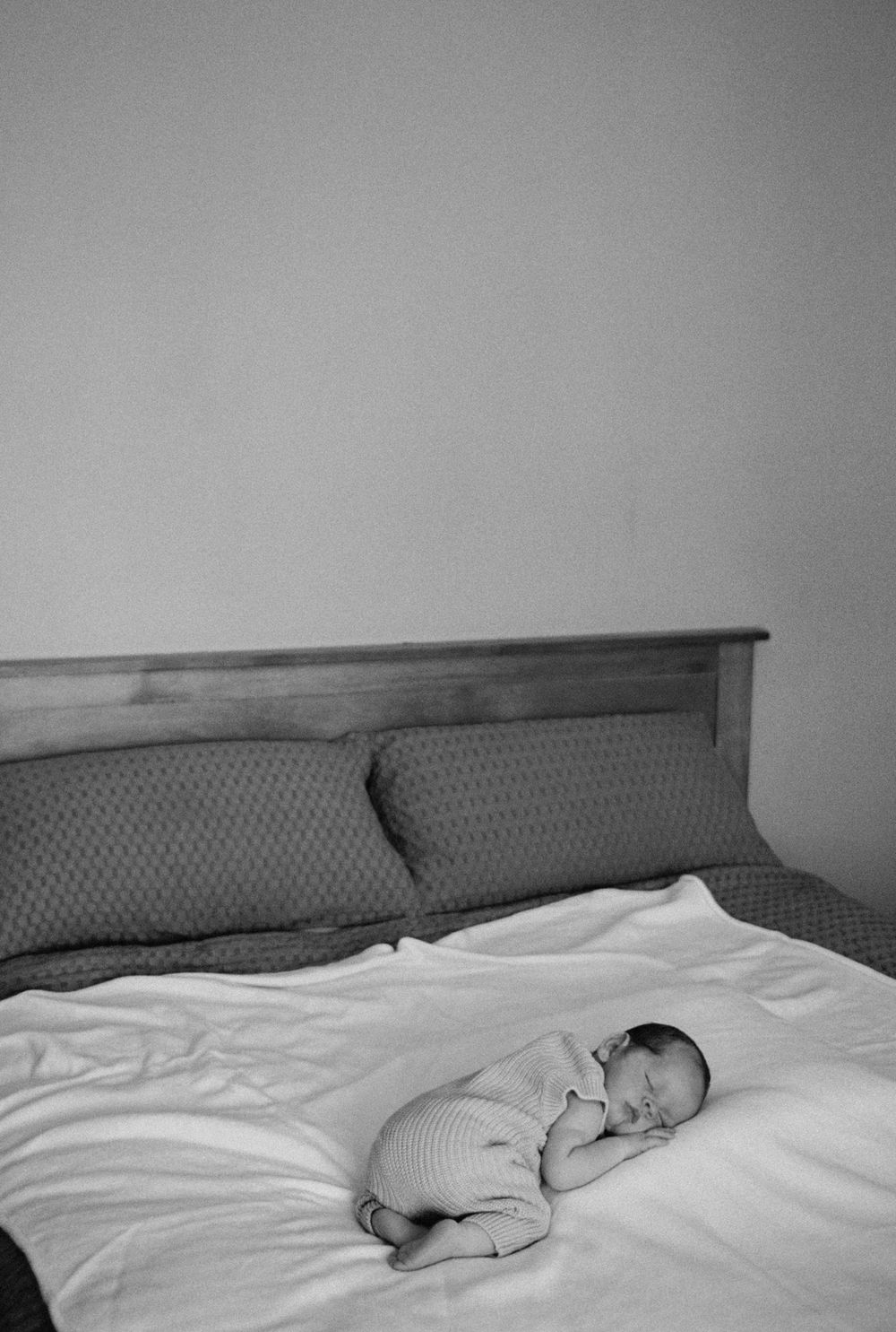 A peaceful image of a sleeping baby lying on white bedding shown in a sequence of monochromatic photos.