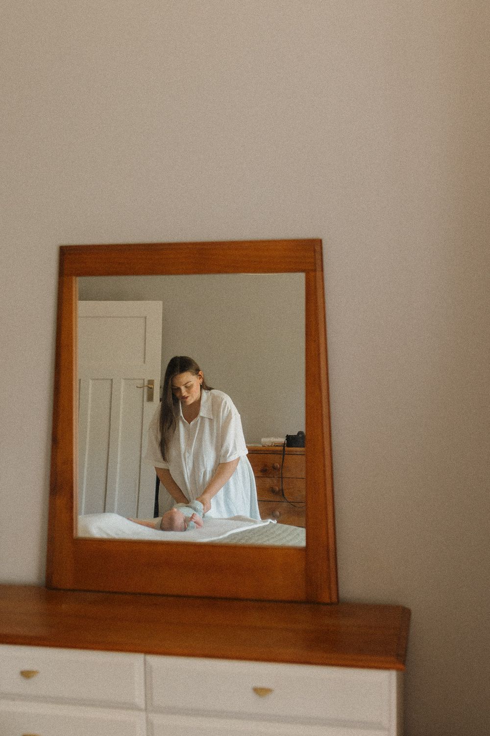 A series of mirror reflections showing someone in white against a wooden framed mirror.