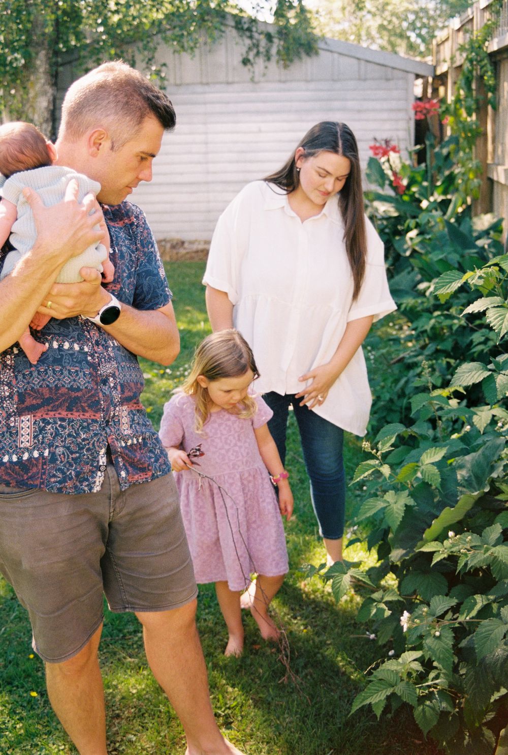 Group looking at plants growing in a backyard garden on a sunny summer day.