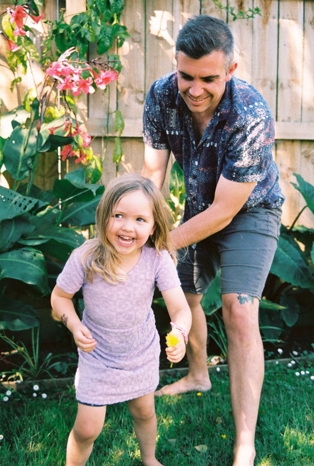 Playful sequence of a child running and laughing in a backyard garden setting.
