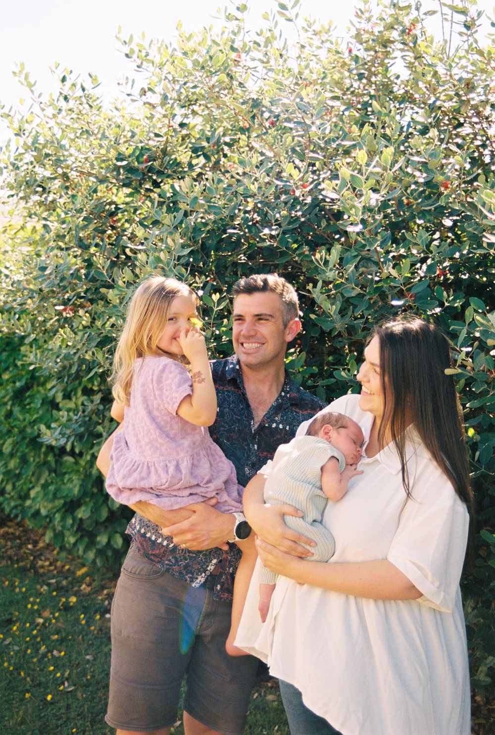 Candid family moments captured in a series of outdoor photos against a leafy backdrop.