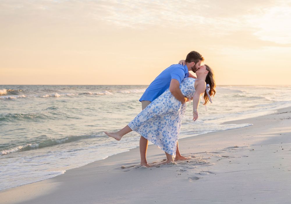 Couple embraces romantically on sandy beach at sunset while ocean waves roll in.