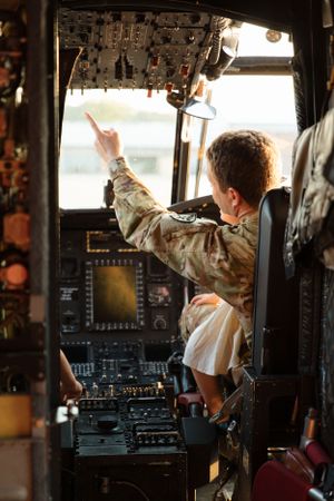 Interior view of military helicopter cockpit with control panels and displays.