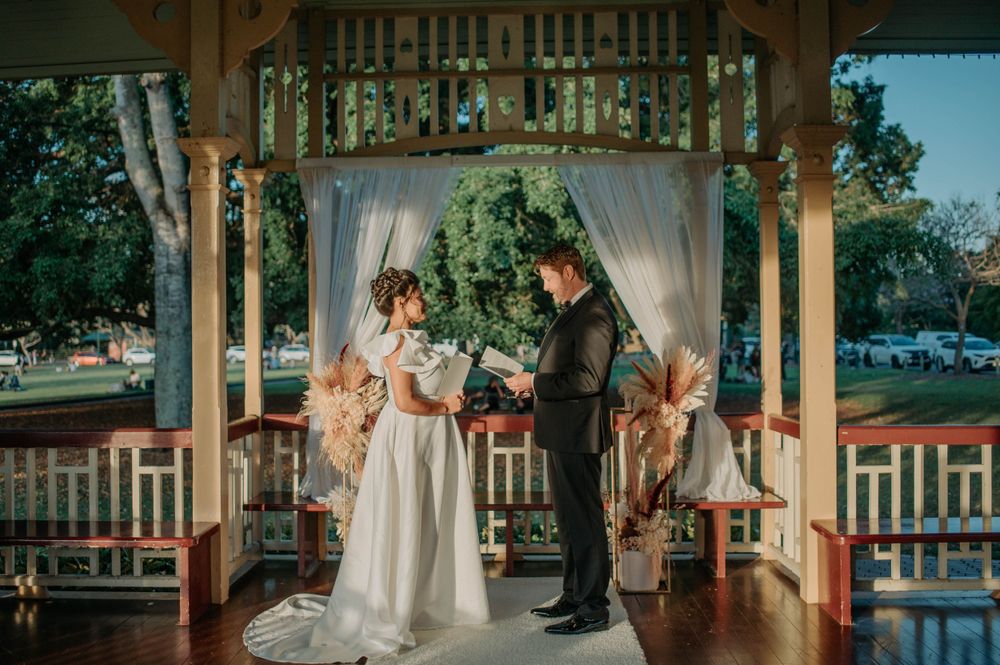 An intimate wedding ceremony captured inside an elegant gazebo with white drapes and floral decorations.