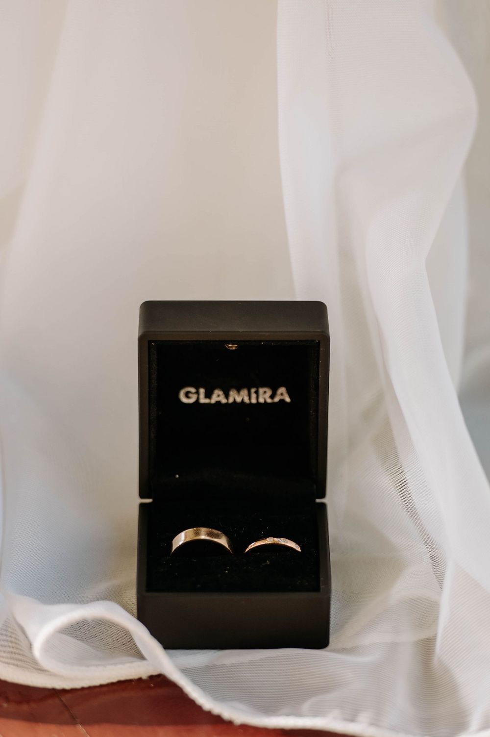 Two wedding rings displayed in a black Glamira jewelry box against white fabric.