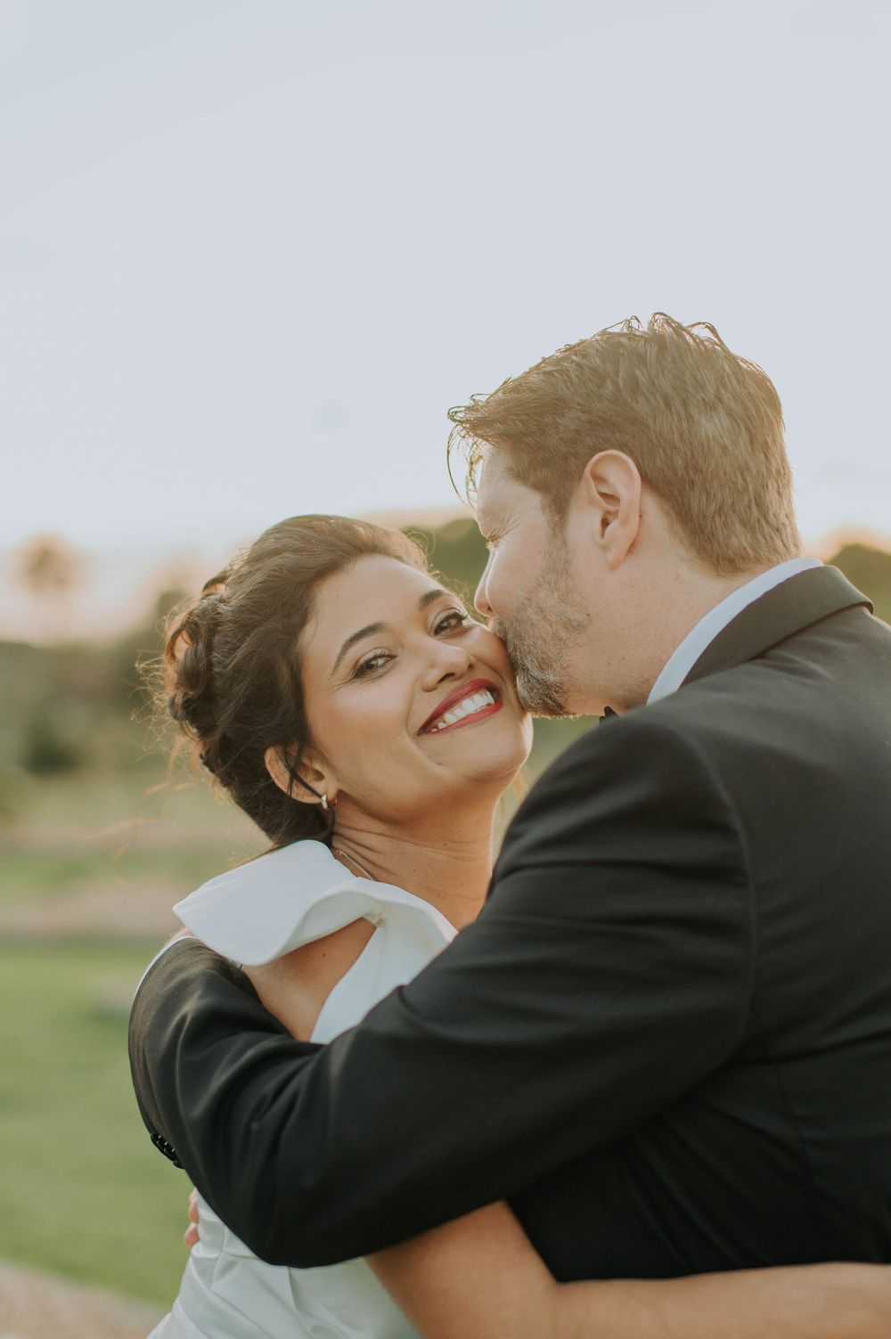 Tender moment between newlyweds captured in warm golden light during sunset portrait session.