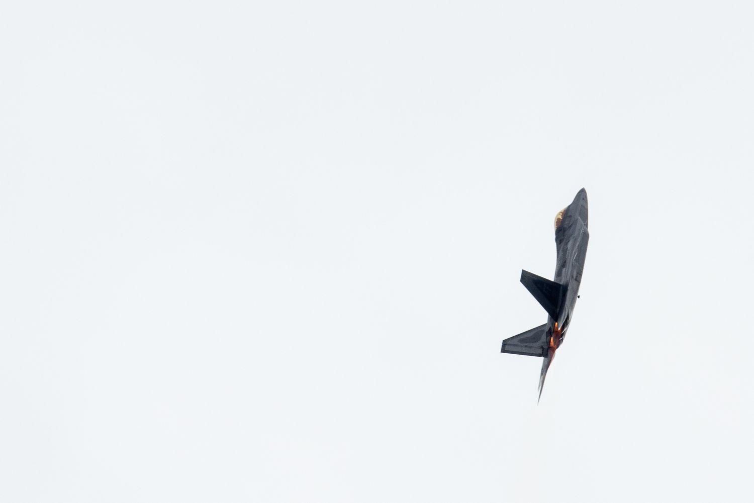 Minimalist composition of a dark aircraft silhouette against white sky.