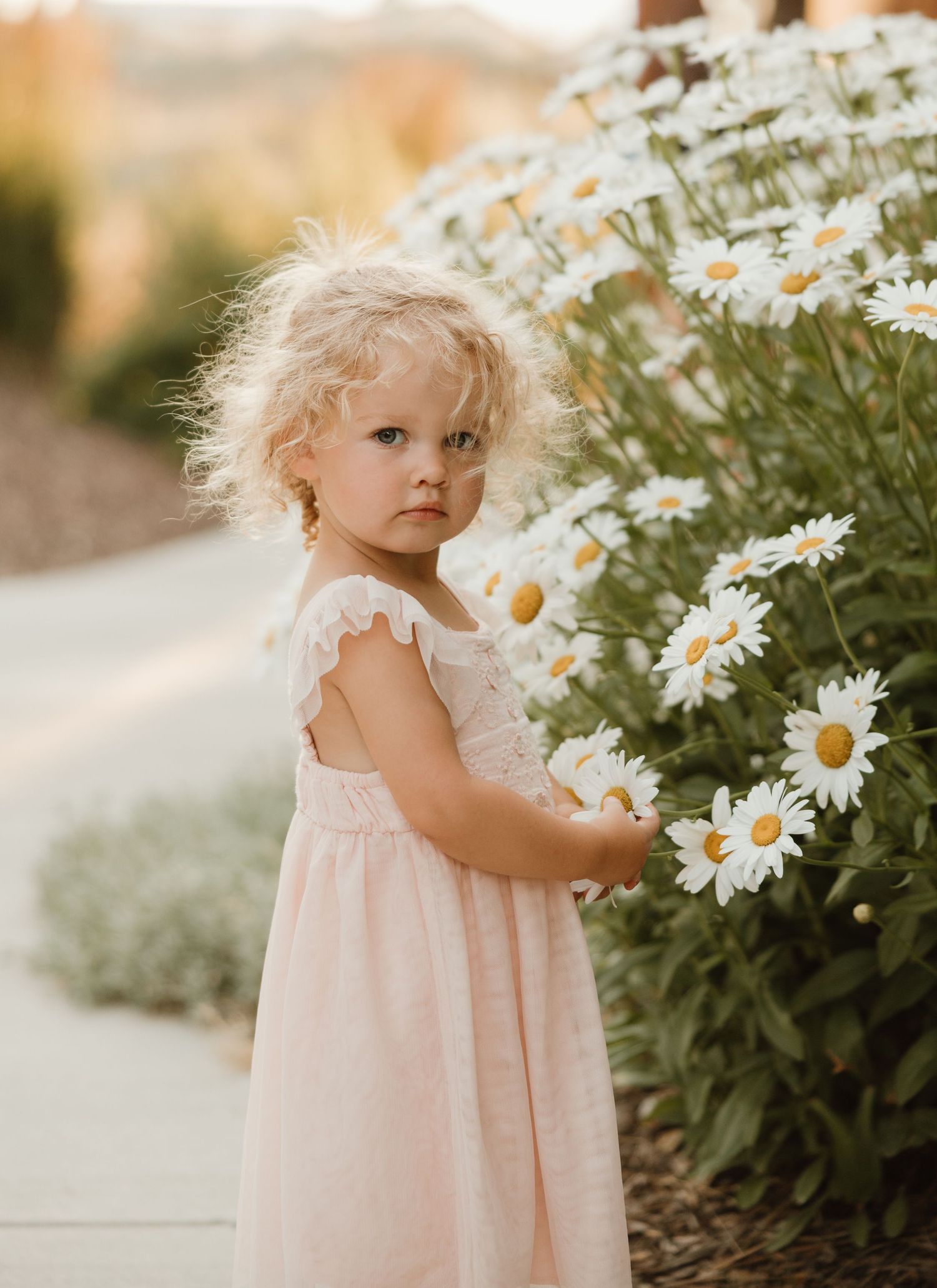 A small child in a light blue dress lies on textured white fabric while gazing upward.