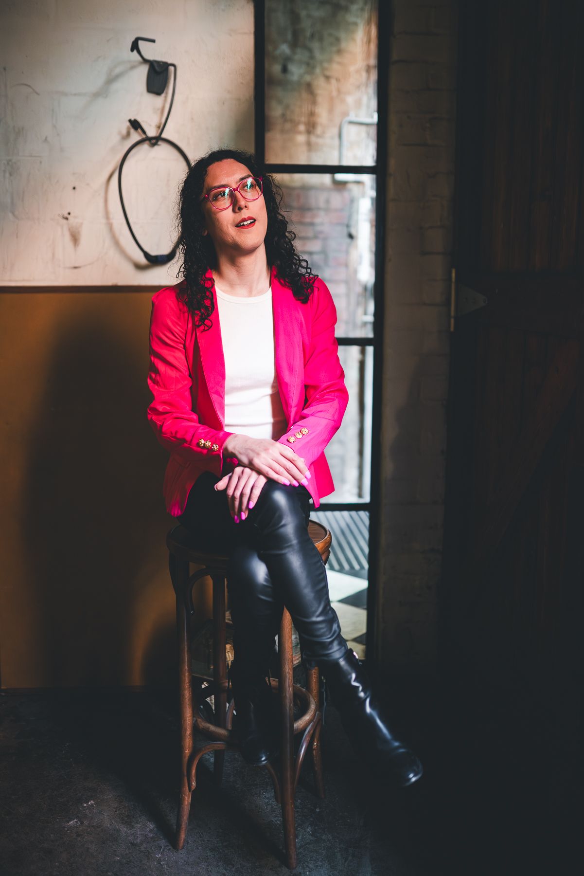 Melbourne branding photo of professional in red blazer, white top & leather pants—moody lifestyle photography in industrial cafe setting.