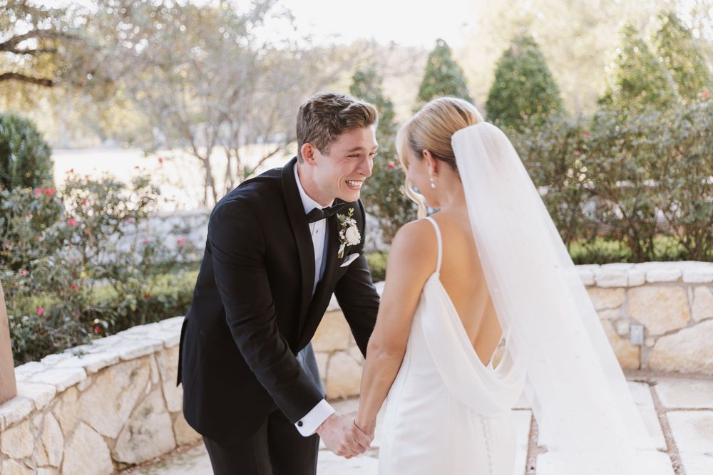 A couple shares a joyful moment together outdoors during their wedding ceremony.