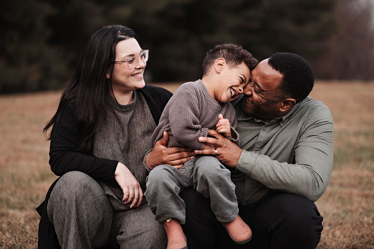 A photograph showing the lifestyle of a joyful family sharing a moment of laughter together while sitting in an autumn field near Hershey PA