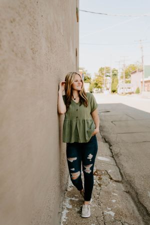 Urban photoshoot featuring distressed jeans and a green top against industrial backdrop.