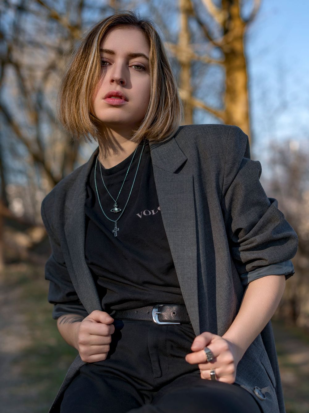 Stylish portrait in autumn setting featuring black t-shirt and oversized gray blazer with golden hour lighting.