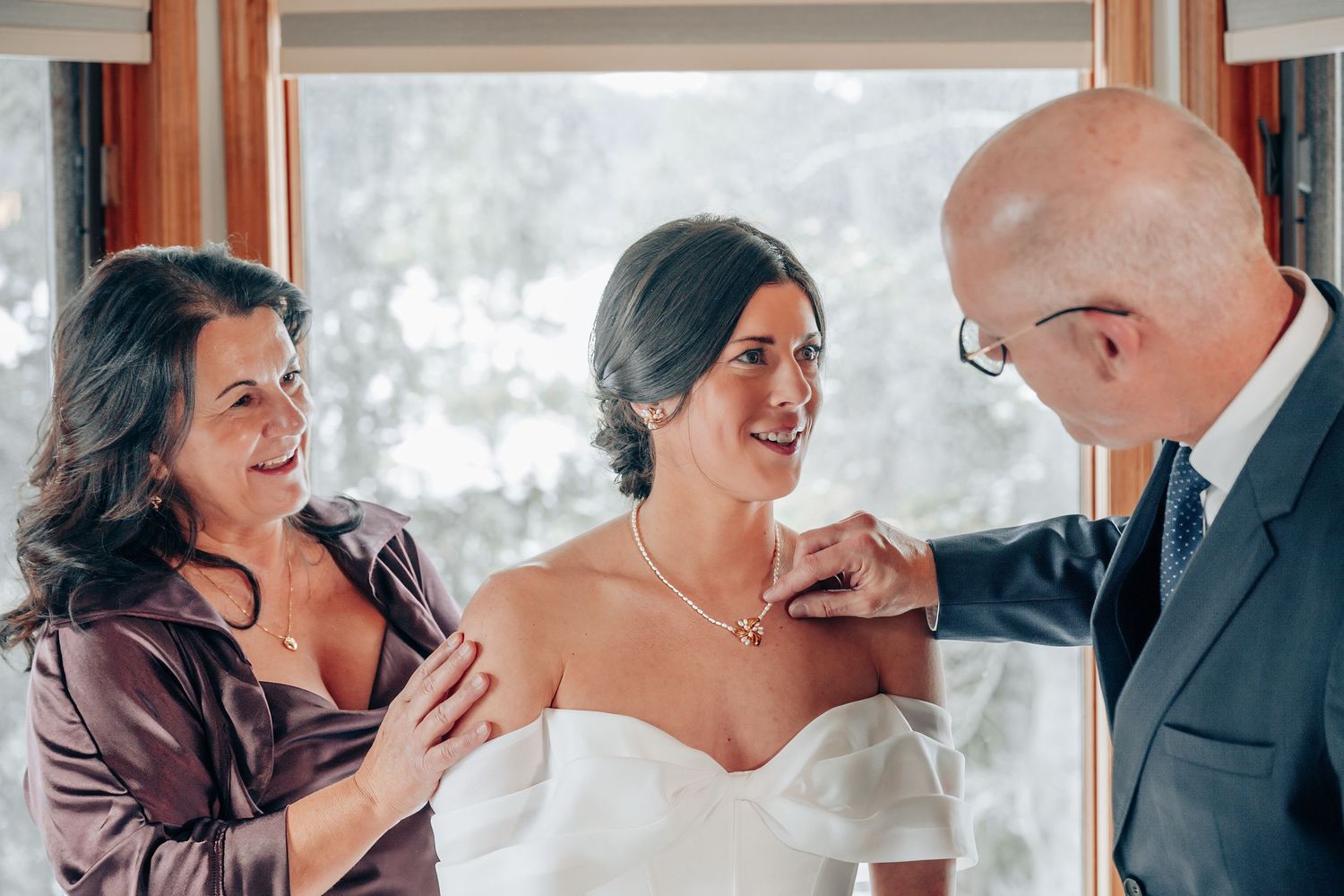 Emotional wedding moment captured by window with soft natural lighting.
