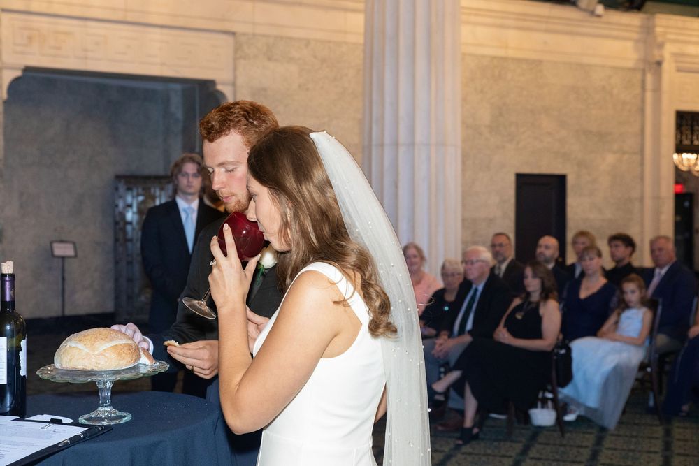 A couple shares their first dance at an elegant wedding reception in a grand ballroom with marble columns.